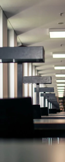 Long row of individual study lamps and desks in a modern Berlin library or study hall, forming a strong perspective. Long row of individual study lamps and desks in a modern Berlin library or study hall, forming a strong perspective.